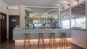 A bar area with stools, a counter, and a variety of bottles. - Asteris Village Gerakini Holiday Resort (Gerakini)