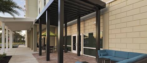 Eine Außenpatio-Terrasse mit überdachter Sitzgelegenheit, einem Weg und einem Gebäude mit Backsteinfassade.