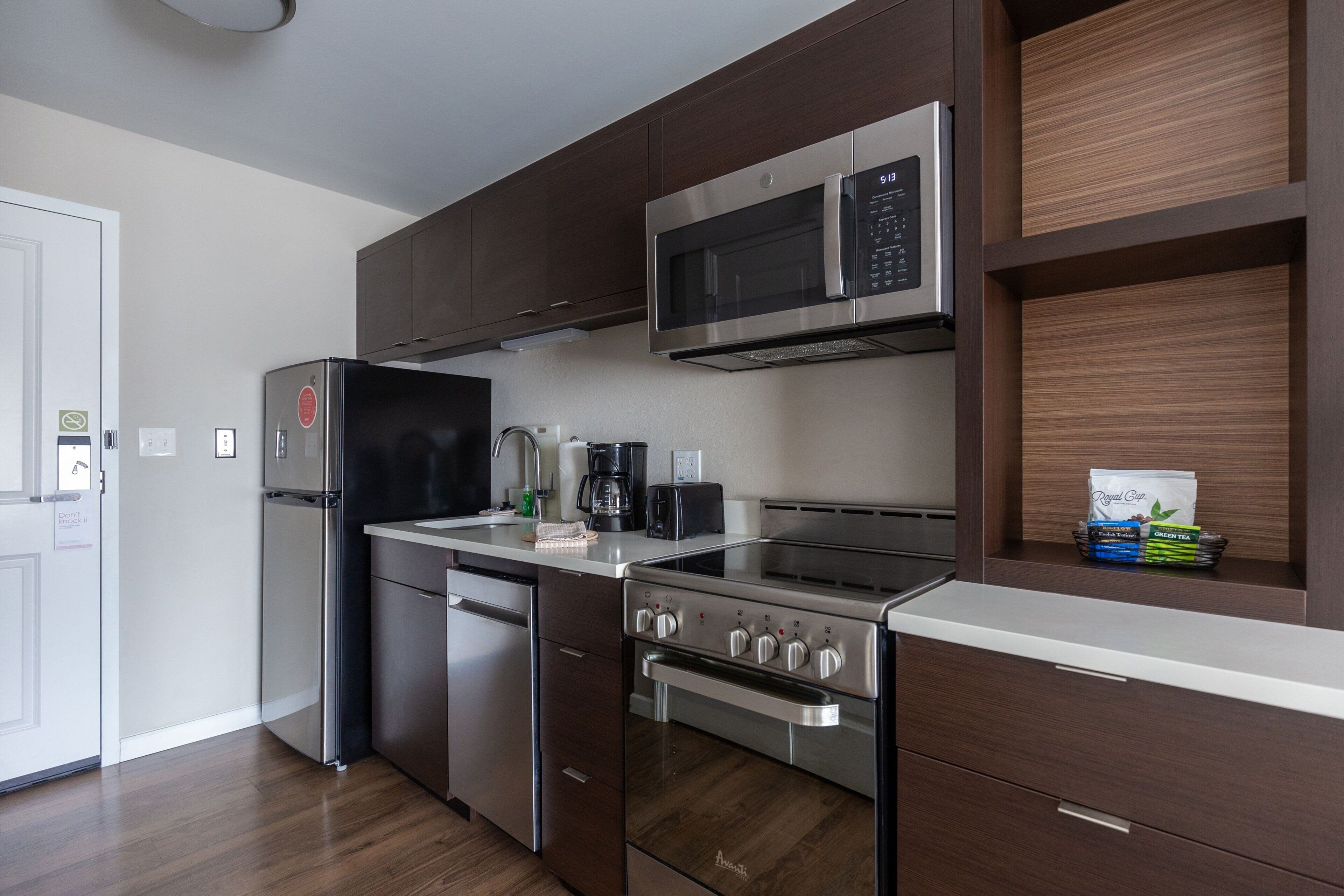 Une cuisine moderne dotée d’appareils électroménagers en acier inoxydable, de meubles en bois et d’un four à micro-ondes encastré.