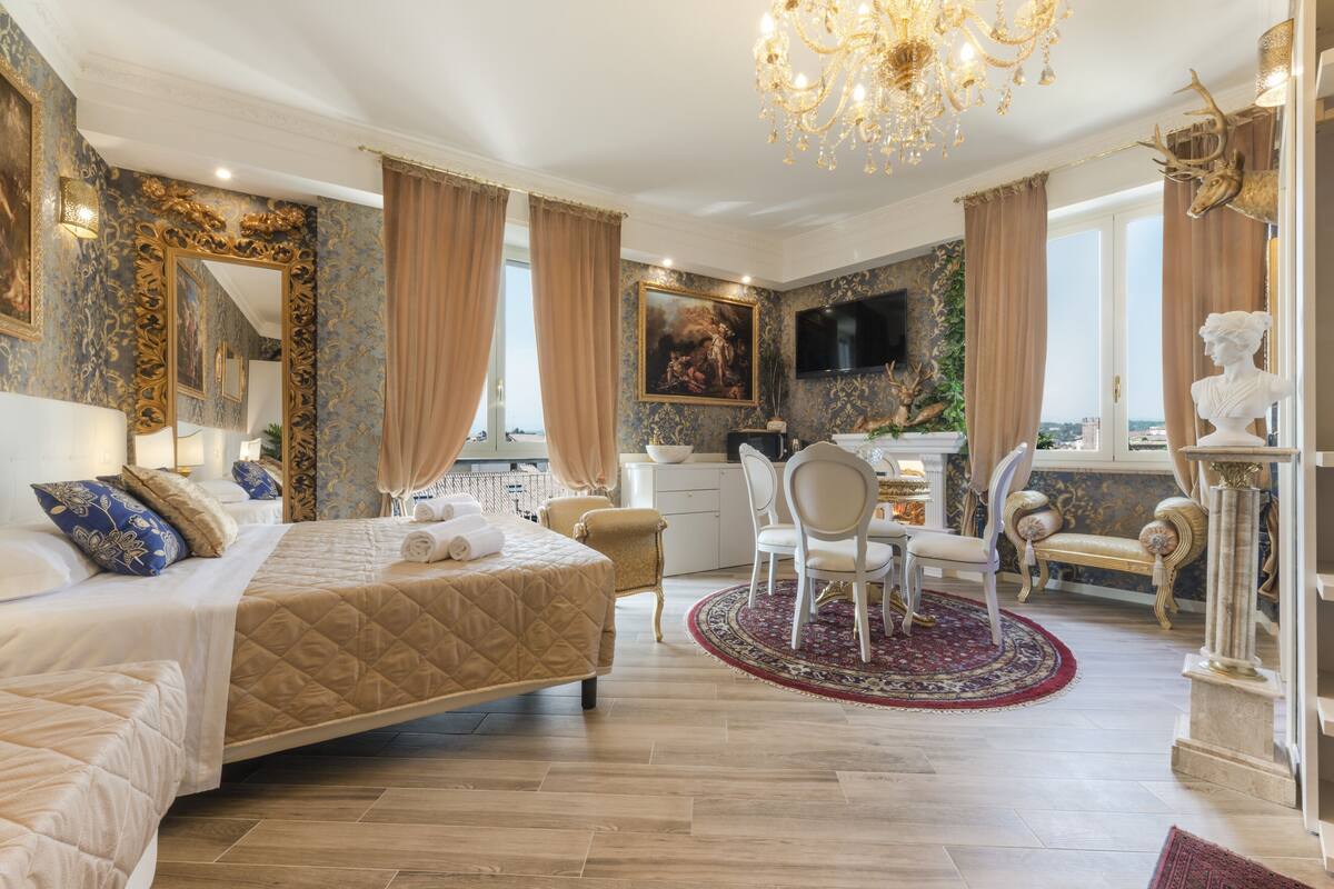 A luxurious bedroom with a large bed, a desk, and a television.