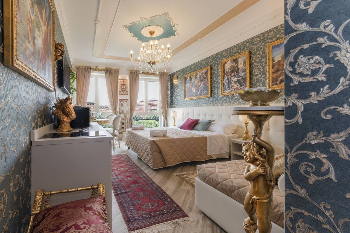 A luxurious bedroom with a large bed, a desk, and a chandelier.