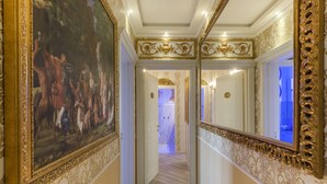 A hallway with ornate gold detailing, a large framed painting, and a mirror reflecting the room. - Olympus Verona Relais (Verona)