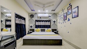 A bedroom with a bed, bedside tables, a mirror, a ceiling fan, and wall decorations. - Treebo Dreamland Guest House (Barasat)