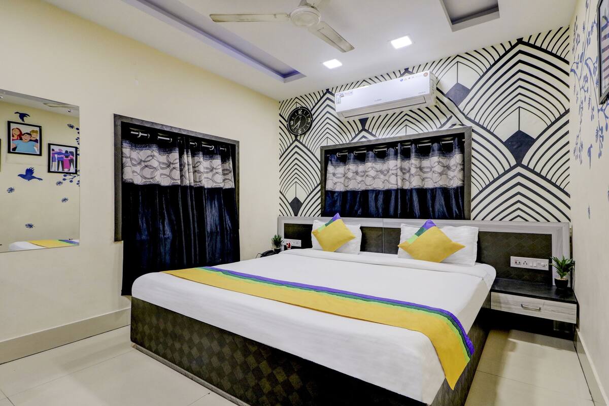 A modern bedroom with a large bed, a ceiling fan, an air conditioning unit, and patterned wall decorations.