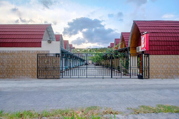 A gated entrance to a building with red roofs and a tiled wall. - OYO Life 1643 Grand Monica (Depok)