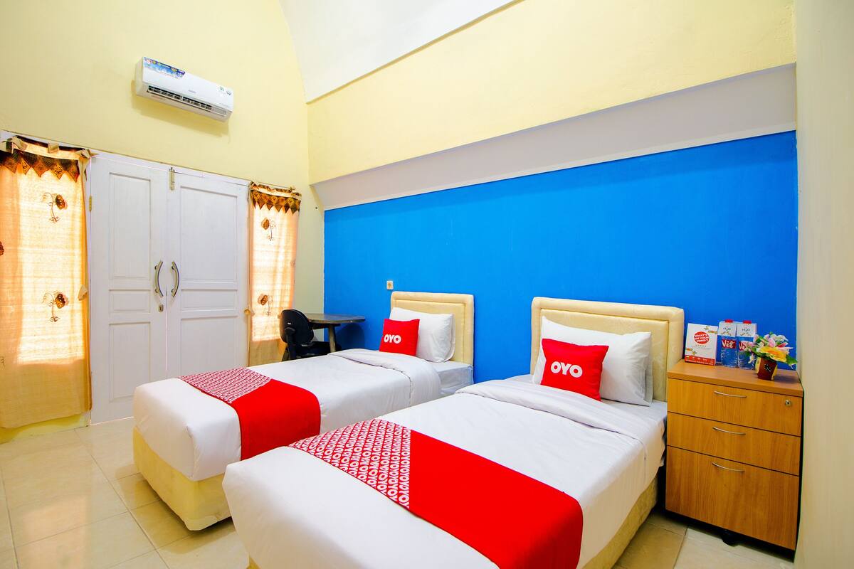 Une chambre d’hôtel avec deux lits, un bureau, une table de chevet et une armoire.