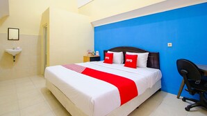 Ein Hotelzimmer mit einem Bett, einem Schreibtisch, einem Stuhl, einem Waschbecken und einem Spiegel.