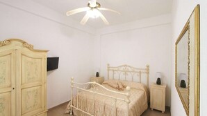 Ein Schlafzimmer mit Bett, Nachttischen, einem Kleiderschrank, einem Deckenventilator und einem Spiegel.