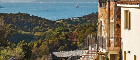 A coastal property with a staircase leading to a balcony overlooking the sea.