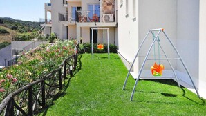 Un immeuble résidentiel doté d’un balcon, d’une balançoire et d’une pelouse bien entretenue.