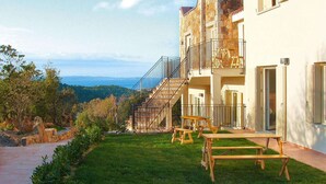 A building with a stone facade, a balcony, and a view of the landscape. - Apartment in Golfo Aranci with terrace (Baja Sardinia (SS))