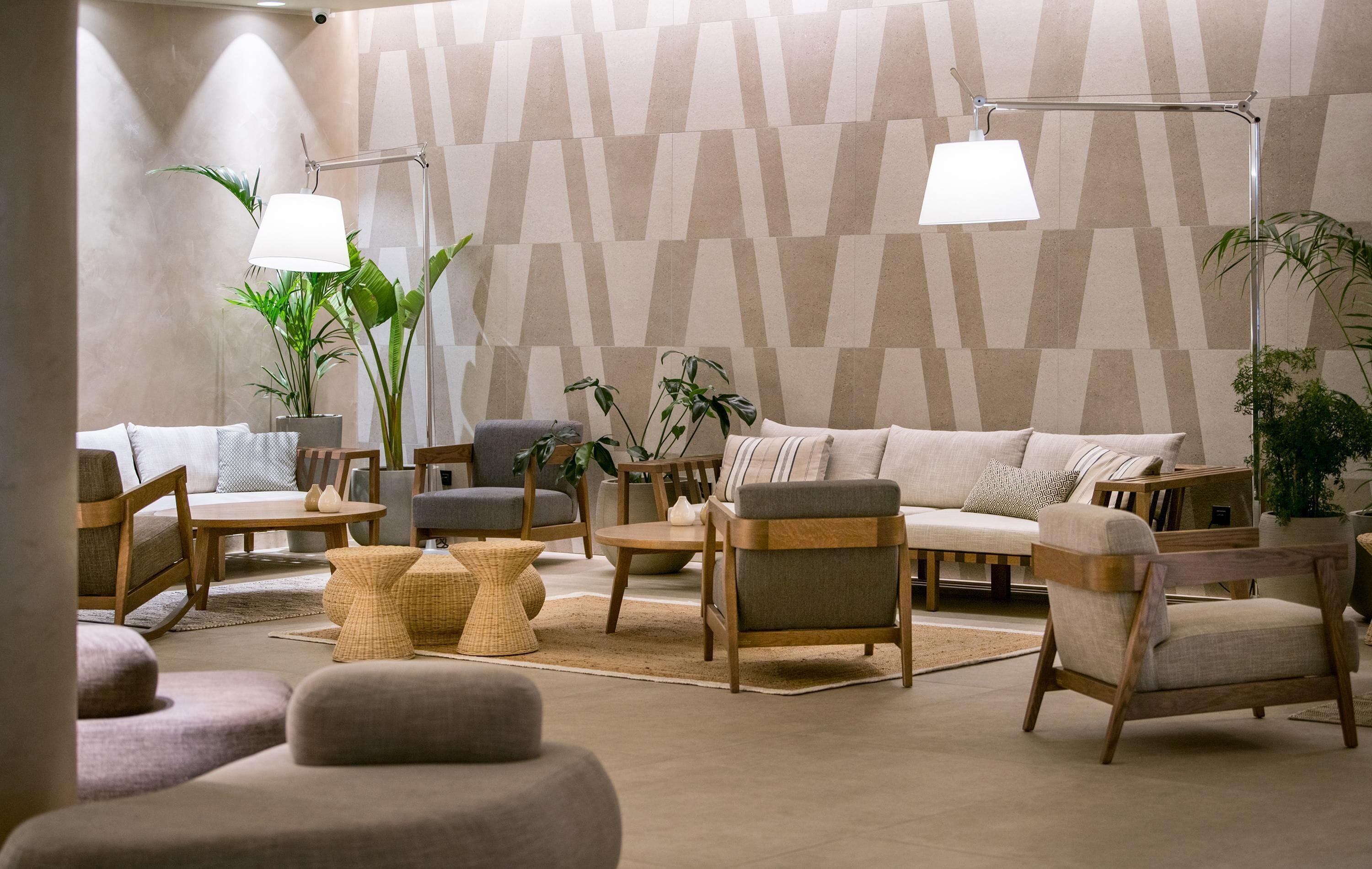 Un moderno salón con una pared de estampado geométrico, muebles de madera y plantas en macetas.