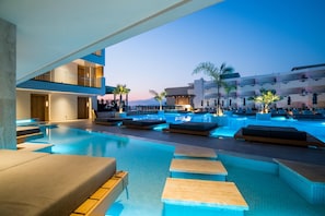 A modern hotel pool area with tiered seating and a view of the surrounding buildings. - Akasha Beach Hotel & Spa (Hersonissos)