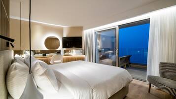 A modern hotel room with a large bed, a desk, a chair, and a balcony with a view.