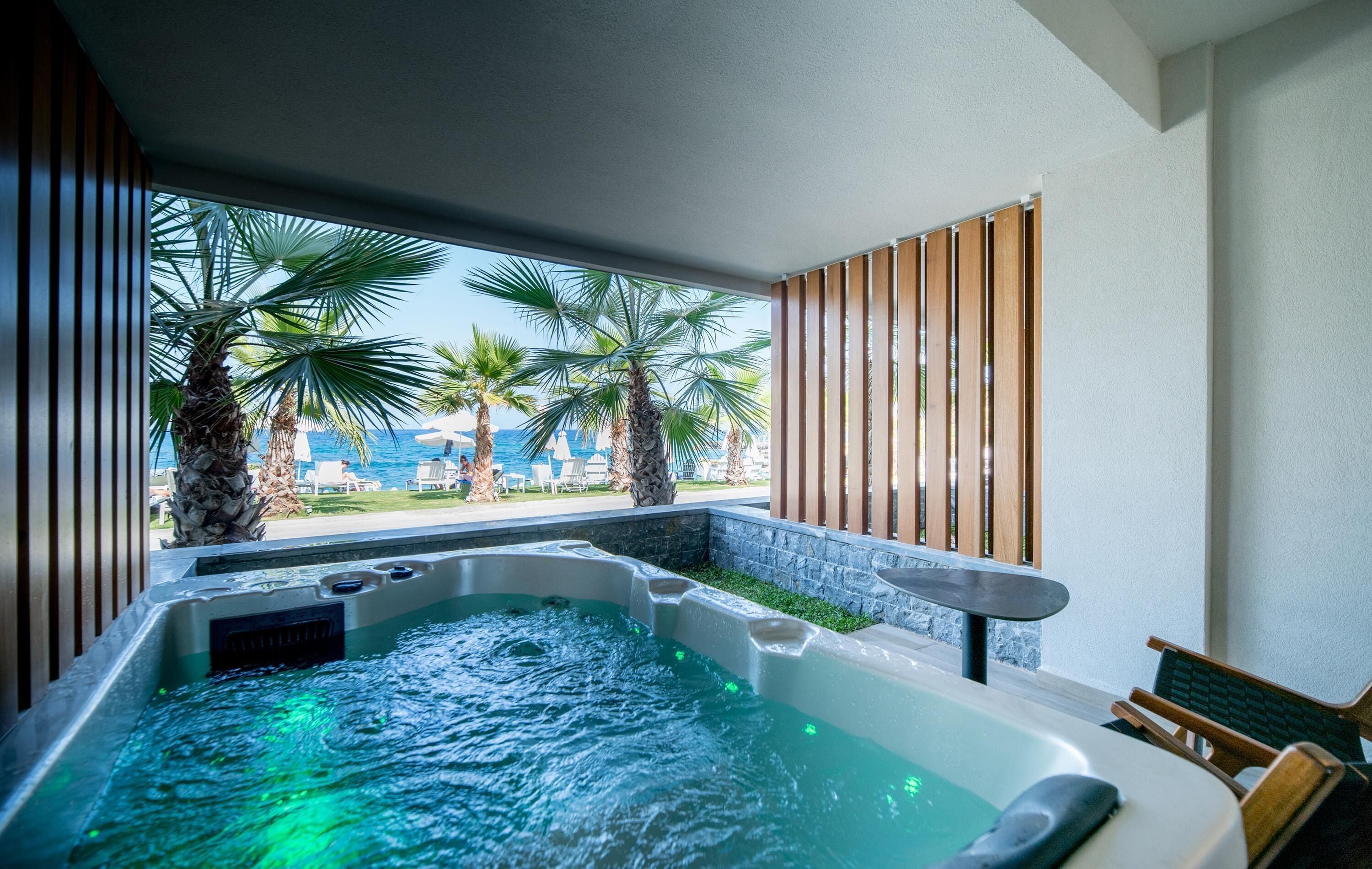 Un jacuzzi con vistas a palmeras y una zona junto a la piscina.