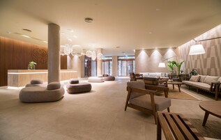A spacious lobby with a reception desk, seating areas, and a large window providing natural light.