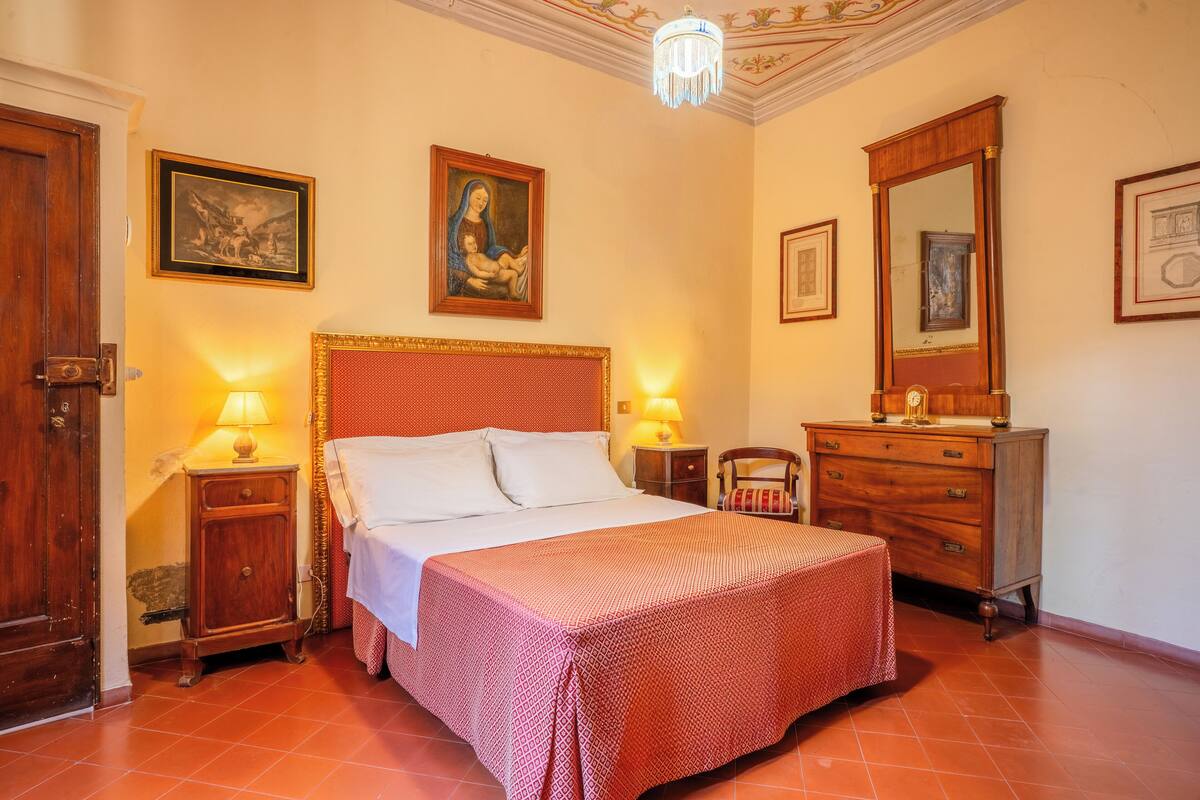 Une chambre d’hôtel avec un grand lit, deux tables de chevet avec des lampes, une commode en bois et un miroir.