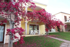 Un bâtiment à la façade jaune, doté d’un balcon et orné d’un arbre aux fleurs roses.