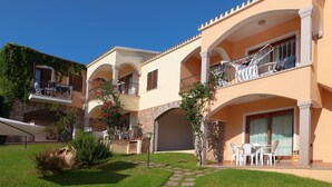 A multi-story hotel with balconies, outdoor seating, and a stone archway. - Apartment in in Badesi with Shared Pool (Badesi)