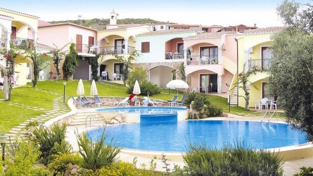 A pool area with a circular pool, lounge chairs, umbrellas, and a small bridge. - Apartment in in Badesi with Shared Pool (Badesi)