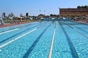 A large outdoor swimming pool with multiple lanes, sun loungers, and umbrellas. - Terrace Vibes in the Italian Sun (Piombino)