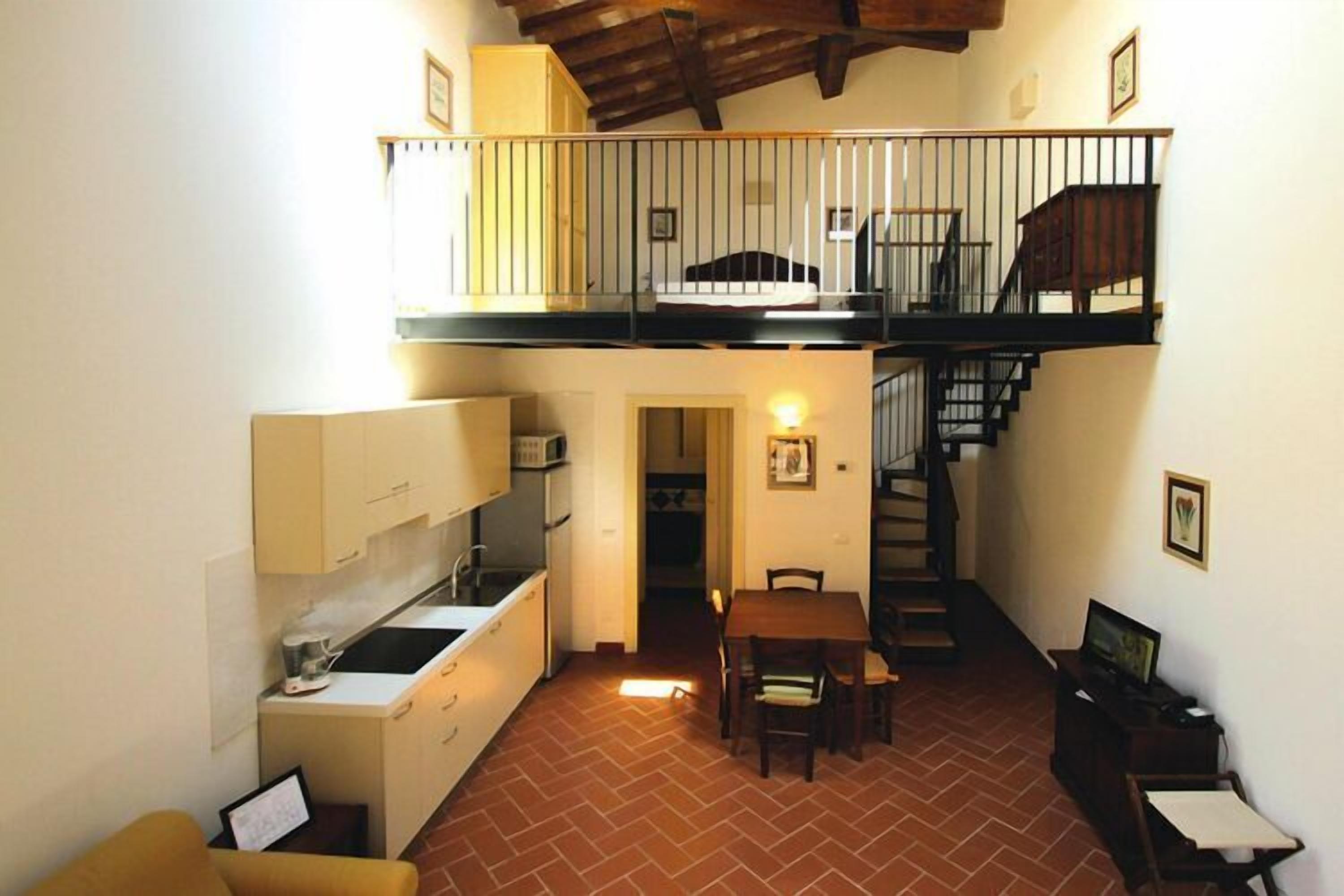 A compact kitchen with a dining area, a staircase, and a small seating area.