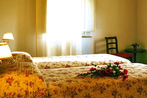 A room with two beds, a chair, a table, and a lamp.