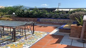 An outdoor patio with a glass table and chairs, surrounded by a tiled floor and brick walls. - Penthouse in the center - Pompeii (Pompei)