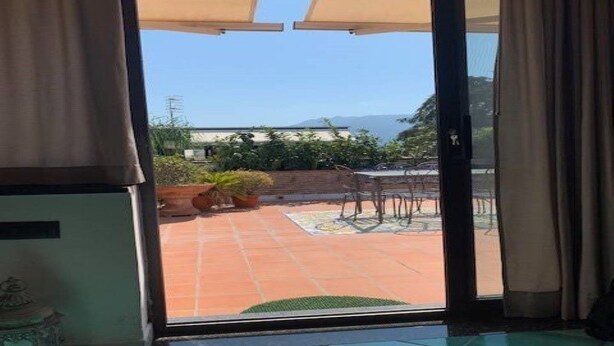 A room with a sliding glass door leading to an outdoor patio with a tiled floor, a small table, and a chair. - Penthouse in the center - Pompeii (Pompei)
