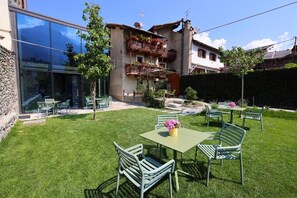A courtyard with a green lawn, outdoor furniture, and a building with balconies. - Relais Bondaz (Aosta)