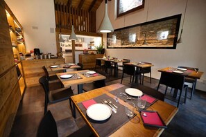 A restaurant with wooden interiors, multiple tables, and a large fish tank on the wall. - Relais Bondaz (Aosta)