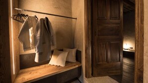 Een gezellige kamer met een houten bank, een kledingrek en een houten deur.
