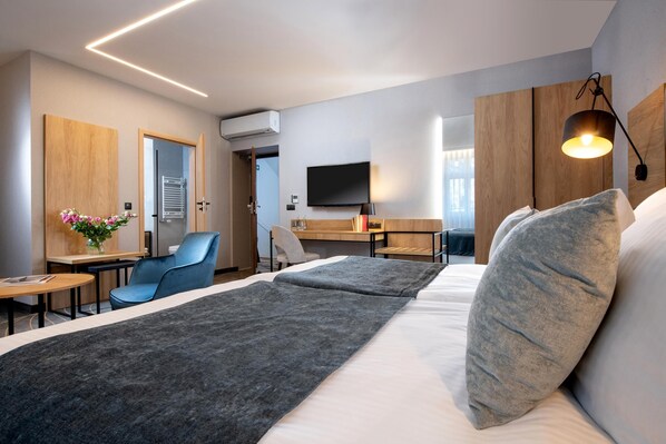 Quarto de hotel moderno com uma cama grande, uma escrivaninha, uma cadeira e uma televisão.