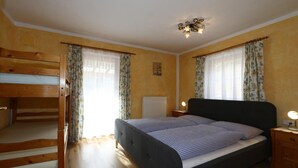 A bedroom with a bunk bed, a single bed, a bedside table with a lamp, and a ceiling light fixture. - Chalet in Grossarltal with Panoramic Views (Großarl)