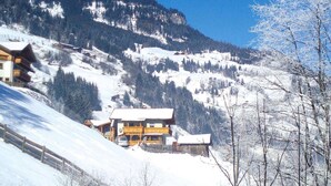A mountain lodge with a wooden exterior, multiple balconies, and a snow-covered landscape. - Chalet in Grossarltal with Panoramic Views (Großarl)