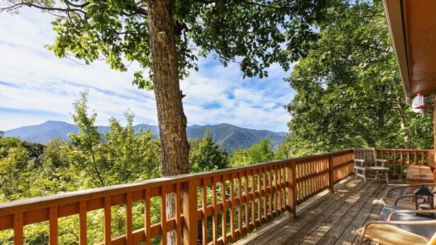 A wooden deck with a railing, outdoor furniture, and a view of mountains. - Skyview Cabin - Spectacular View, 2 BR, 2 1/2 BA, Brand New Hot Tub, Firepit (Maggie Valley)