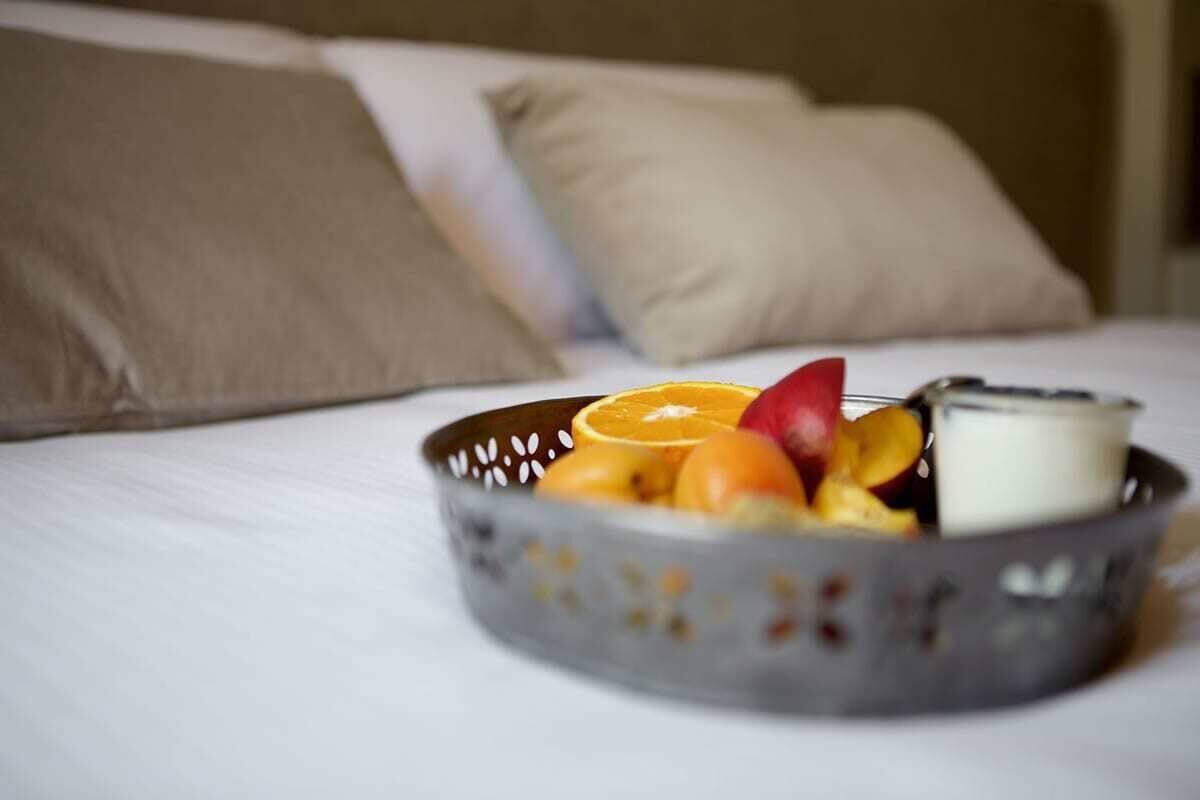 A bed with a basket of fruit and a glass of milk on it.