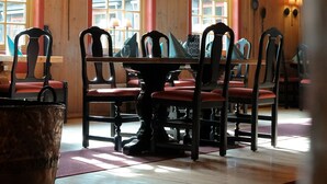 A wooden dining area with a high ceiling, wooden beams, and a table set for six. - Hunderfossen Snøhotell (Lillehammer)