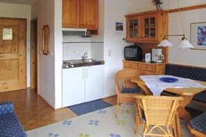 A compact kitchen with wooden cabinets, a sink, and a dining area with a table and chairs.