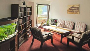 A living room with a bookshelf, a fish tank, a sofa, and a coffee table. - Apartment in Wildschönau by Schatzberg Lift (Wildschönau)