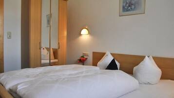 Une chambre d’hôtel avec un lit, une armoire, une table de chevet avec une lampe et un tableau au mur.