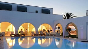 A swimming pool with lounge chairs and umbrellas, surrounded by a building with arched openings. - Hotel Sporting (Casalbordino)