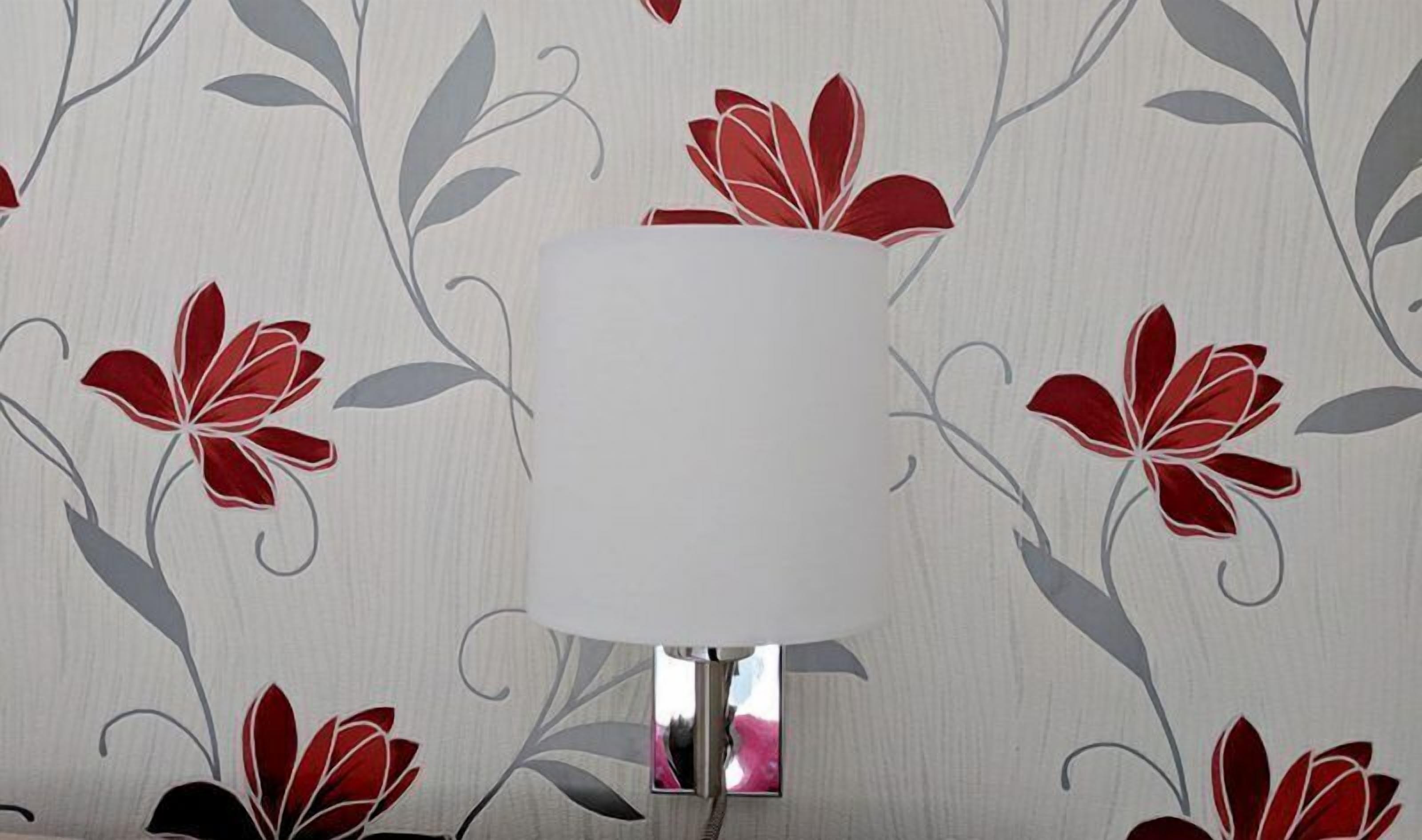 Une pièce dont un mur est blanc et orné d’un papier peint à motifs floraux.