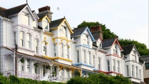 A row of Victorian-style houses with distinct color accents on the facades. - Sea Tang Guest House (Brixham)