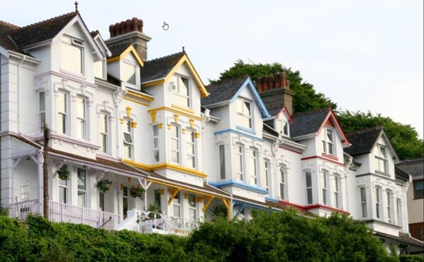 A row of Victorian-style houses with distinct color accents on the facades. - Sea Tang Guest House (Brixham)