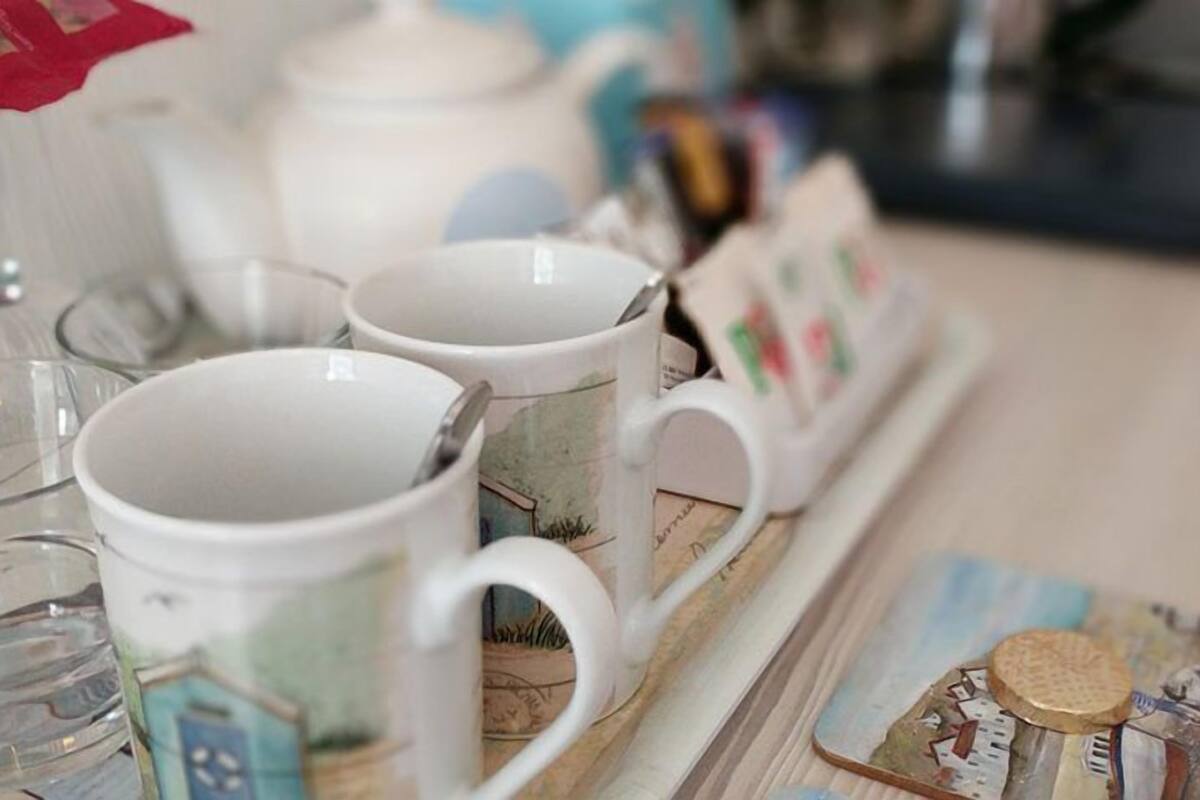 A tray with various ceramic mugs and a teapot, some with printed designs.