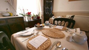 A dining table set with plates, cutlery, and a teapot, with a menu on the table. - Sea Tang Guest House (Brixham)