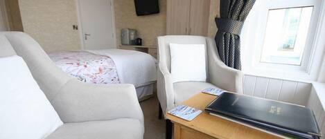 Habitación de hotel con dos camas, un escritorio, una silla, un televisor y una ventana con cortinas.