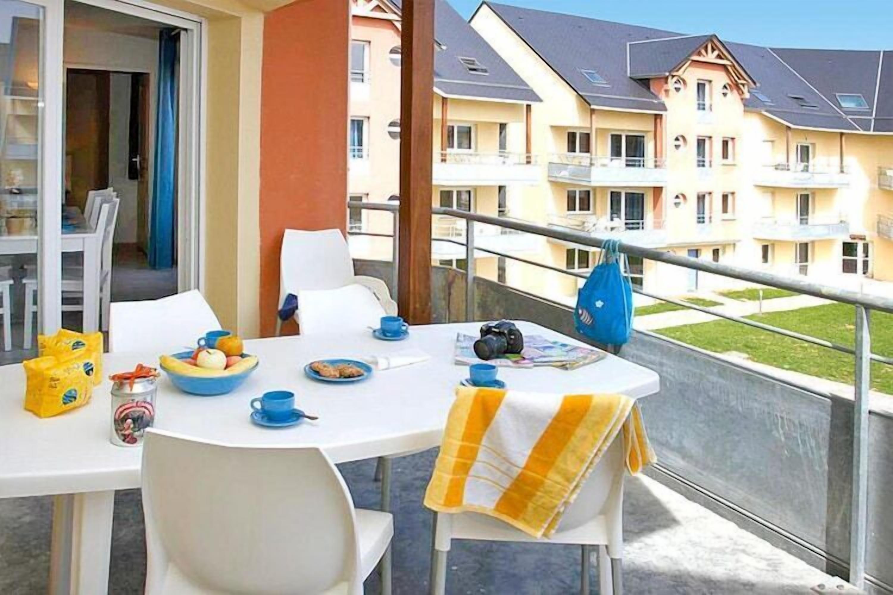 Un balcón con una mesa dispuesta para el desayuno, una cámara y una bolsa azul.