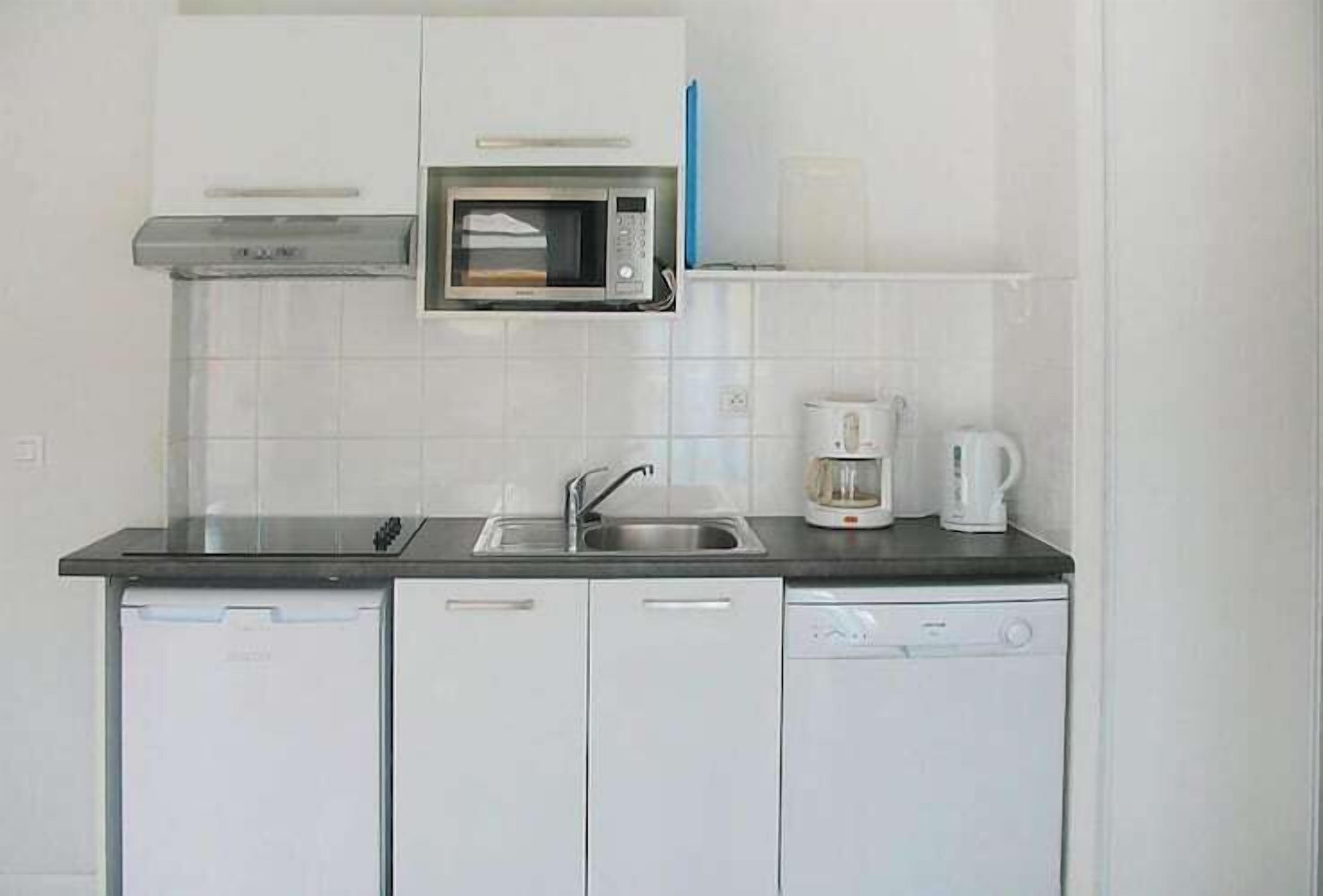 Una cocina compacta equipada con microondas, cafetera y lavavajillas.